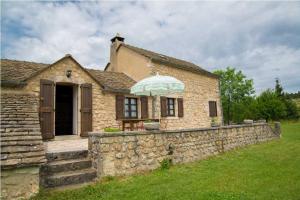 a stone house with an umbrella over a stone wall at Gîte de poujols in Mas Saint-Chély