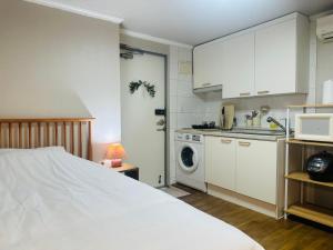 a bedroom with a white bed and a kitchen at Stay Cozy Corner Gangnam, Suseo, Ilwon-dong, Samsung Hospital, a 7-minute walk from Daecheong Statio in Seoul