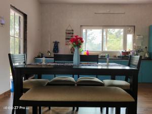 a dining room table with chairs and a vase of flowers at Huvazeel Villa - Murbad for Monthly rental only in Saralgaon +16 photos