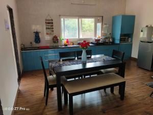 a kitchen with a table and chairs and a kitchen with blue cabinets at Huvazeel Villa - Murbad for Monthly rental only in Saralgaon