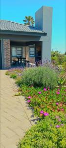 ein Garten mit rosa Blumen vor einem Haus in der Unterkunft Gasteria Cottage in Mossel Bay