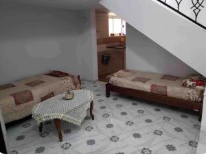 a room with two beds and a table in a room at F2 Maison avec jardin à Constantine in Hamma Bouziane