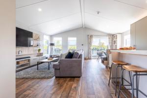 a living room with a couch and a kitchen at Tranquil Woodland Lodge Retreat in Lincolnshire in Woodhall Spa