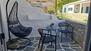 a patio with two chairs and a table and a swing at OFIOYSA KaGa kythnosuites in Mérikhas