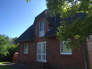 a red brick house with a white door at Christiansand in Norddorf