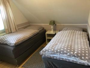 a bedroom with two beds and a table with a lamp at Christiansand in Norddorf