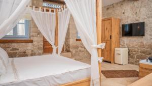 a bedroom with a bed with a canopy and a tv at otel alba Alaçatı in Cesme