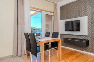 a dining room with a table and chairs and a television at Apartment Iva in Veli Iž
