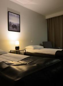 una camera d'albergo con due letti e una foto a parete di Kylpylähotelli Kiannon Kuohut a Suomussalmi