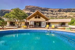 a house with a swimming pool in front of a mountain at SaffronStays Eagle's Span in Malavli