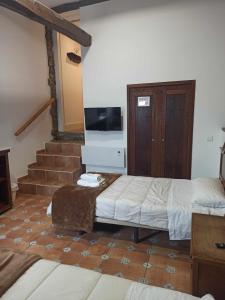 Pokój z dwoma łóżkami, telewizorem i schodami w obiekcie Casa Taboada w mieście Sarria +30 zdjęć