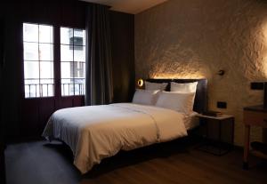 a bedroom with a bed with white sheets and a window at Letoh Letoh Bilbao in Bilbao