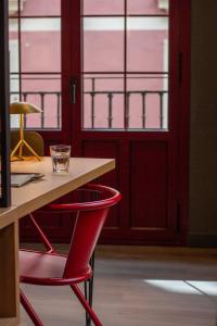 a red chair sitting next to a table with windows at Letoh Letoh Bilbao in Bilbao