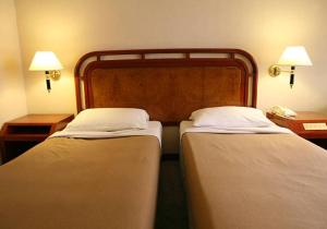 two beds in a hotel room with two lamps at Hotel New Kesar Palace in Agolai