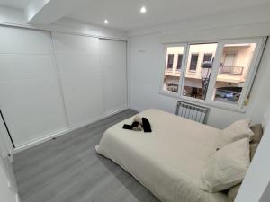 a white bedroom with a bed and a window at Apartamento Oviedo Centro in Oviedo
