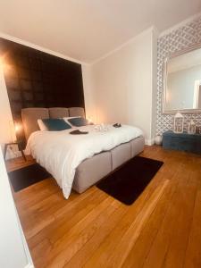 a bedroom with a large white bed and wooden floors at La Galerie, suite pour 2 personnes avec chambre supplémentaire possible in Saint-Fargeau