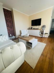 a living room with a white couch and a tv at La Galerie, suite pour 2 personnes avec chambre supplémentaire possible in Saint-Fargeau