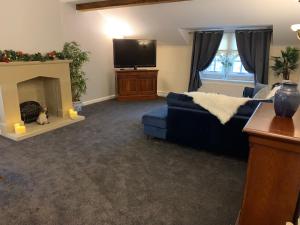 a living room with a blue couch and a tv at Santo's Higham Farm Hotel in Alfreton