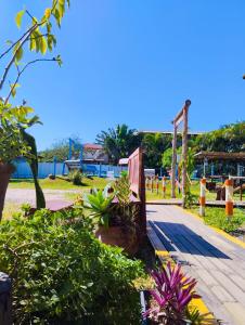 a garden with plants and a wooden boardwalk at Pousada Horizontes do Rosa in Praia do Rosa +228 photos