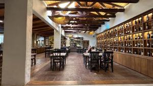 a dining room with tables and chairs and a wall of wine bottles at Hotel Villa El Descanso Express in Curicó