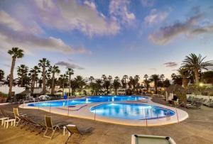 una gran piscina con sillas y palmeras en Las Brisas Villa 106, en Playa Blanca