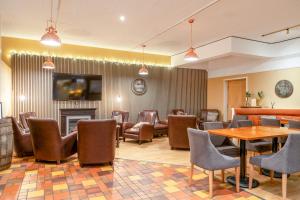 a waiting room with tables and chairs and a fireplace at Coylumbridge Resort Hotel in Aviemore +42 photos
