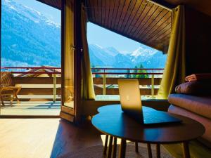 カンデルシュテークにあるAmazing River and Mountain View Apartmentのバルコニー付きの客室で、テーブル上のノートパソコンを利用できます。