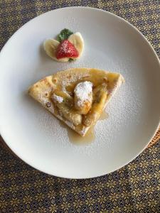 a white plate with a piece of pancake and a strawberry at Villa Manis Segare in Julah