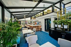 a restaurant with white tables and chairs and plants at Hotel Old Town in Batumi