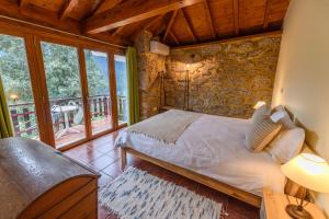 una camera da letto con un letto e un balcone di Gerês Country Stays - Sequeiro a Rio Caldo