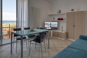 a living room with a table and chairs and a television at Aurora d'Elysium in Spotorno
