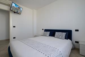 a bedroom with a white bed with a tv on the wall at Aurora d'Elysium in Spotorno