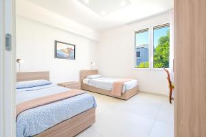 two beds in a white room with two windows at Le Cammire Luxury Apartment - Leuca in Leuca +31 photos