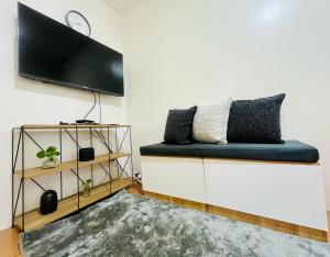 a living room with a bench with a flat screen tv at Wanderer's Home at Seawind Condo near Davao Airport in Davao City