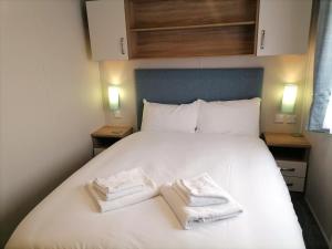 ヘイスティングスにあるBeauport Holiday Parkの白いベッドとタオルが2枚置かれた寝室