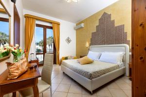 a bedroom with a bed and a table and a desk at Hotel La Darsena in San Vito lo Capo +57 photos