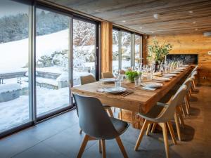 a long wooden table in a room with windows at Chalet Colombine - OVO Network in Les Villards-sur-Thônes +28 photos