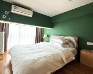 a bedroom with a green wall with a bed and a fan at April Fair Duplex Apartment Guagnzhou South Railway Station Min Jie Branch in Guangzhou