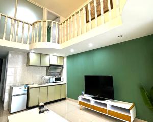 a kitchen with green walls and a large television at April Fair Duplex Apartment Guagnzhou South Railway Station Min Jie Branch in Guangzhou