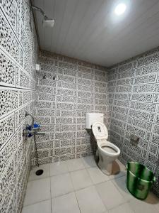 ein Bad mit einem WC in einer gefliesten Wand in der Unterkunft VINTAGE HOMES, Darjeeling in Darjeeling