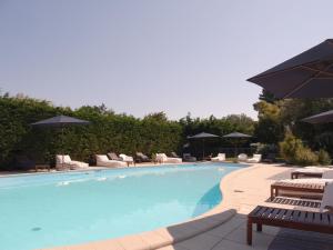 a large swimming pool with chairs and umbrellas at Le Parc des Mimosas in Noirmoutier-en-l'lle