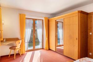 a bedroom with orange curtains and a chair and a window at Alpenblick Tilly - Fewo Barmsee 2 in Krün