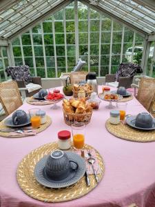 a table with a pink table cloth with baskets of food at Le Clos de l'Ambre in Divajeu