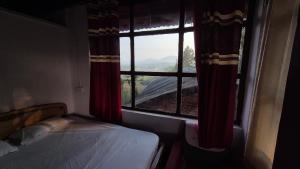 a bedroom with a window with a view of a mountain at Coorg Tribal Land homestay in Kushālnagar