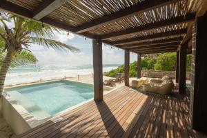 an outdoor deck with a swimming pool and the beach at Casa Aakbal - Luxury Beach Front Villa in Tulum