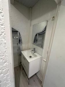 une salle de bain blanche avec un lavabo et un miroir dans l'établissement Timounyan T1 N23 centre ville Animaux acceptés, à Arcachon