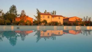 a house is reflected in a pool of water at La Beccanina Resort in Le Case