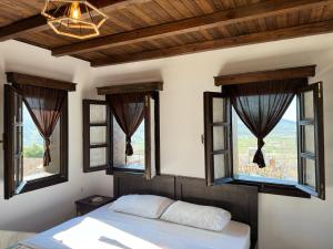 a bedroom with windows and a bed with white sheets at Bujtina Bega in Berat