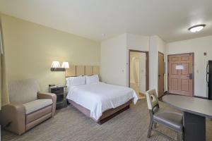 タルサにあるAffordable Suites of America Tulsaのベッドと机と椅子があるホテルの部屋