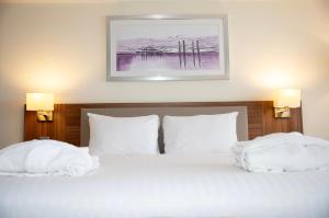 a bedroom with a bed with white sheets and pillows at Holiday Inn Brighton Seafront by IHG in Brighton & Hove